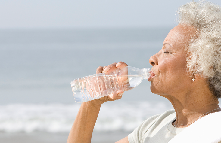 black woman drinking water at a beach